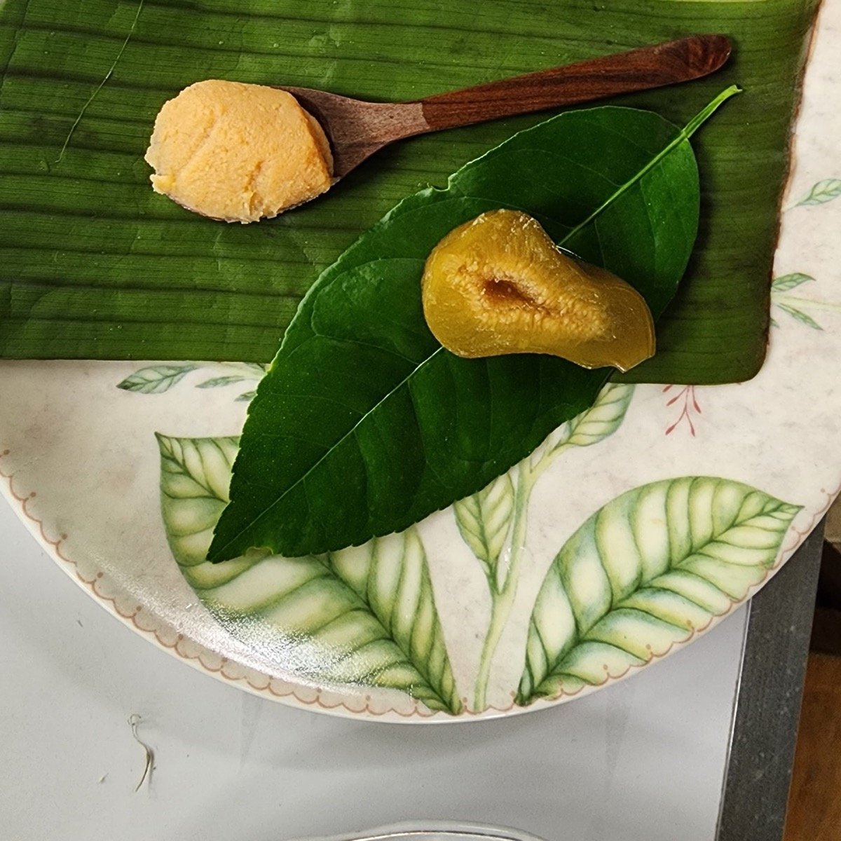 Manjar blanco en cuchara de madera y dulce cortado sobre hoja de plátano, dulces caseros del Valle del Cauca